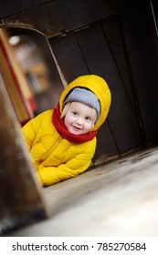 Cute Little Boy Having Fun On Outdoor Playground. Toddler Playing Inside Wooden Child Hut Or Small House. Spring, Autumn Or Winter Active Leisure For Kids.