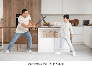 Cute little boy and his father playing with toy swords in kitchen - Powered by Shutterstock