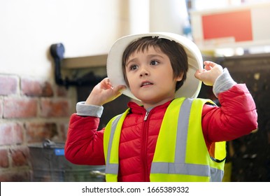 Cute Little Boy Holding Helmet And Reflective Vest, Child Pretending A Worker Constrution Wearing Safety Jacket And Helmets Costume, Play And Learn Concept