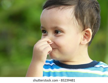 Cute Little Boy Holding His Nose In Green Nature