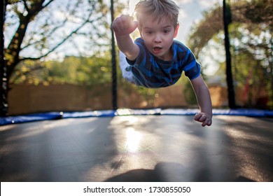 Cute little boy jumping on the trampoline like a superhero, he believes he can fly, summer family vacation. Outdoor fun and healthy activity, people enjoy life after lockdown