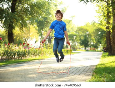 Cute Little Boy Jumping Rope In Park