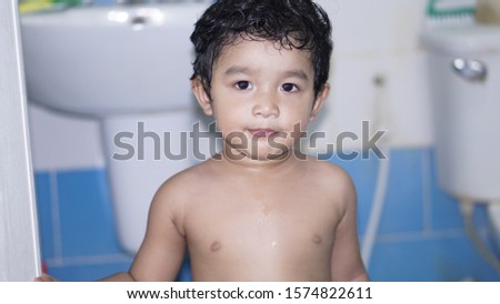 Cute of little boy kid Asian baby​ 2 year old or 22 month standing to looking something He does not wear a shirt his body and face wet. He ready to take a shower.