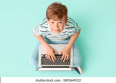 Cute little boy with laptop on color background. Concept of online education