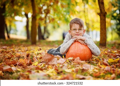 Cute little boy  leaning on a pumpkin, autumn time