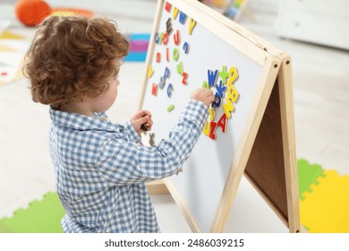 Cute little boy learning alphabet with magnetic letters on board in kindergarten - Powered by Shutterstock