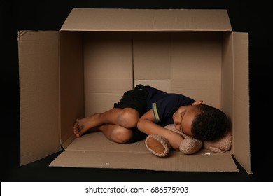 Cute little boy living in box on dark background. Poverty concept - Shutterstock ID 686575903
