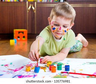 Cute Little Boy Painting On Floor At Home