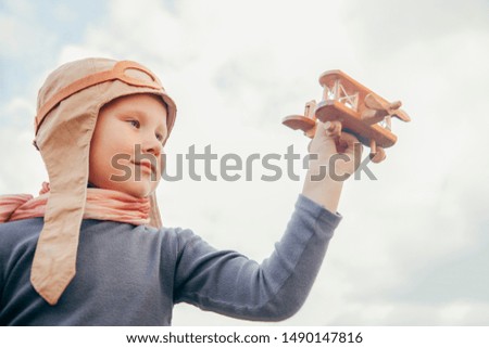 cute little boy in a pilot's suit is playing with a toy plane near the airport