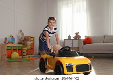 Cute little boy playing with big toy car and stuffed bunny at home