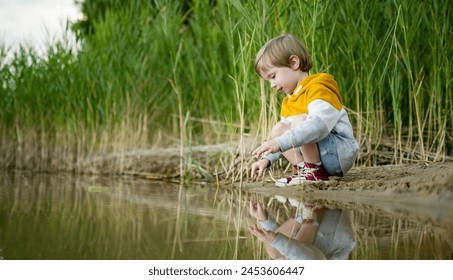 Cute little boy playing by a lake or river on hot summer day. Adorable child having fun outdoors during summer vacations. Water activities for kids. - Powered by Shutterstock