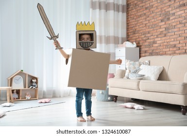 Cute little boy playing cardboard armor in living room