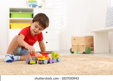 Cute little boy playing with colorful toys on floor at home, space for text