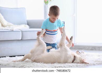 Cute Little Boy Playing With Dog At Home