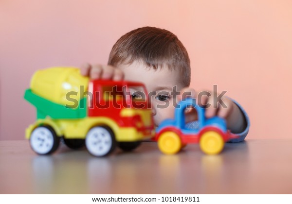 A cute little boy\
playing with model car collection. Toy mess in child room.\
Educational games for kids.
