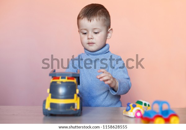 A cute little boy\
playing with model car collection. Toy mess in child room.\
Educational games for kids.
