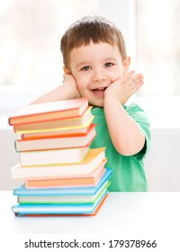 Cute little boy is reading book while sitting at table, indoor shoot - Shutterstock ID 179378966