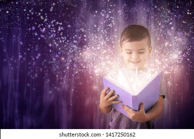 Cute little boy reading magic book on dark color background