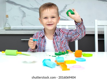 A cute little boy sculpts from plasticine on the table. The boy is playing in his room. Educational toys for children. Games for the development of the child.Children's hands knead plasticine.