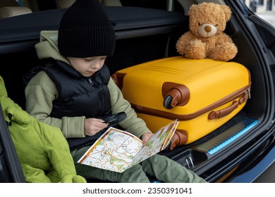 Cute little boy sitting in a car trunk before going on vacations with parents. Kid looking forward for a road trip or travel. Autumn break at school. Family travel by car. - Powered by Shutterstock