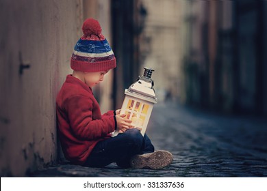  Cute little boy, sitting on the street, holding lantern - Powered by Shutterstock