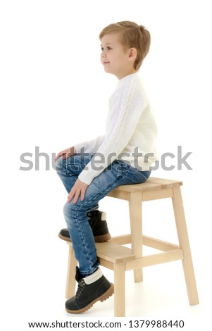 A cute little boy is sitting on a chair. Isolated on white background.