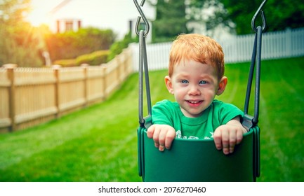 Cute little boy sitting in swingset at sunset