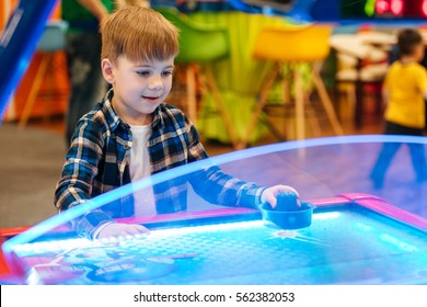 Cute Little Boy Standing And Playing Air Hockey At Indoor Amusement Park