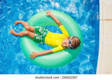 Cute little boy swims in a pool in an green life preserver - Shutterstock ID 250422307