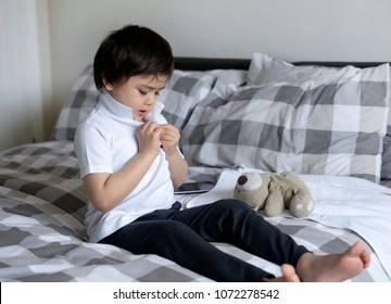 Cute Little Boy Trying To Close White Polo Shirt Buttons, School Kid Sitting In Bed With Teddy Bear Tried To Button Up His School Polo Shirt, Cute Boy Getting Dressed And Get Ready For School, 