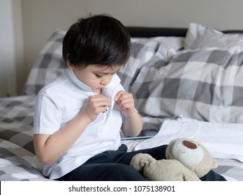 Cute Little Boy Trying To Close White Polo Shirt Buttons, School Kid Sitting In Bed With Teddy Bear Tried To Button Up His School Polo Shirt, Cute Boy Getting Dressed And Get Ready For School.