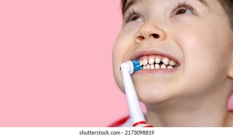 Cute Little Boy Using Electric Toothbrush For Daily Teeth Cleaning.pink Background,close Up,wide Banner.dental Care,dentist For Kids Concept. Smiling Boy, Diastema,space Between Teeth.