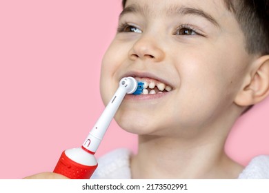 Cute Little Boy Using Electric Toothbrush For Daily Teeth Cleaning.pink Background,close Up,wide Banner.dental Care,dentist For Kids Concept. Smiling Boy, Diastema,space Between Teeth.