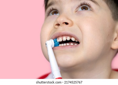 Cute Little Boy Using Electric Toothbrush For Daily Teeth Cleaning.pink Background,close Up,wide Banner.dental Care,dentist For Kids Concept. Smiling Boy, Diastema,space Between Teeth.