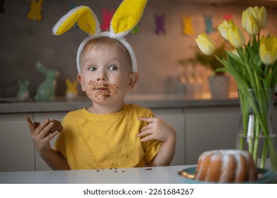 A cute little boy wearing bunny ears on Easter day is eating a chocolate Easter bunny. A child plays egg hunt for Easter. Charming child celebrates Easter at home. - Powered by Shutterstock - Get 15% off with code: PIKWIZARD15