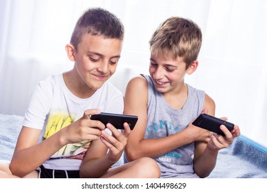 Cute  little boys, brothers playing online games on their smart phones. Modern child activity