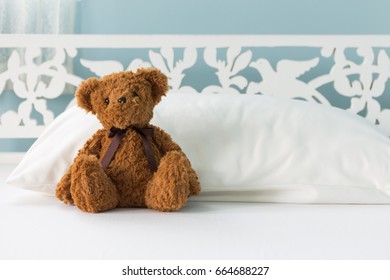 Cute little brown teddy bear sitting on the bed 