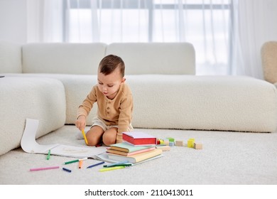 Cute little caucasian boy drawing and colorful pencils  sitting floor at home  alone  Creativity concept  Adorable nice child in domestic clothes having fun  enjoying holidays  weekends 