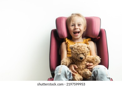 Cute little caucasian girl fastened with a belt in a safety car seat isolated on white background. Kid safety while traveling by car. Happy toddler girl holding teddy bear. Adventure concept - Powered by Shutterstock