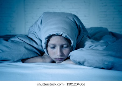 Cute little caucasian girl lying in bed covering her head with blanket feeling exhausted and sleepless suffering from insomnia Depression Stress in Children Emotional and Sleeping Disorders concept.