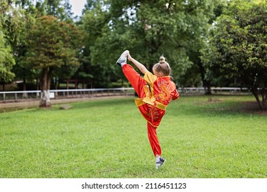 Cute Little Caucasian Girl Seven Years Old In Red Sport Wushu Uniform Exercising In Park At Summer Day. Lifestyle Portrait Of Kung Fu Fighter Child Athlete