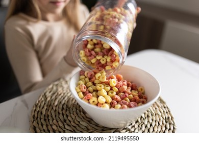 Cute little caucasian girl sitting at table on kitchen early morning and preparing breakfast with colorful cornflakes and milk. Kid enjoying life with healthful food, healthy lifestyle concept - Powered by Shutterstock