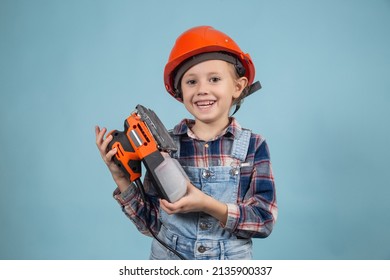 Cute Little Caucasian Kid Is Wearing Orange Safety Helmet,holding Electric Sander At Hands. Concept Of Construction And Repair.