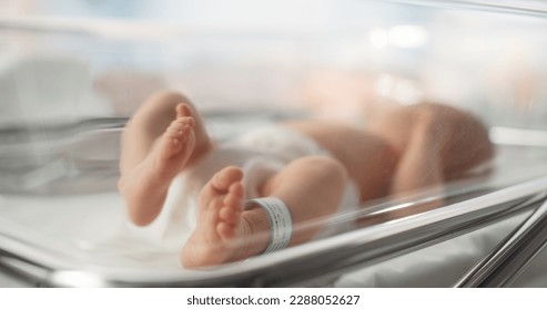 Cute Little Caucasian Newborn Baby Lying in Bassinet in a Maternity Hospital. Portrait of a Tiny Playful and Energetic Child with a Name ID Tag on the Leg. Healthcare, Pregnancy and Motherhood Concept - Shutterstock ID 2288052627