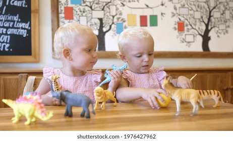 Cute Little Caucasian Twin Sisters Play Together With Toy Animals At The Nursery.