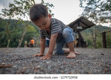 Cute Little Child With Bare Foot Playing On A Ground In Natural Parkland Of Huay Ta Bo Water Reservoir In Chanthaburi Province East Of Thailand, Small Kid Getting Up From A Ground