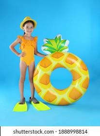 Cute Little Child In Beachwear With Inflatable Ring On Light Blue Background