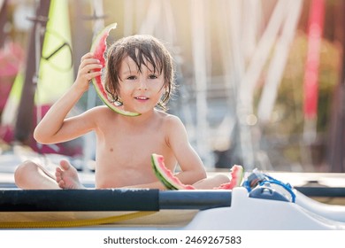 Cute little child, boy, eating watermelon on the beach, summertime - Powered by Shutterstock