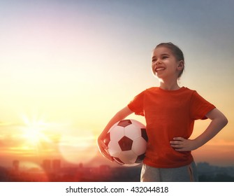 Cute little child dreams of becoming a soccer player. Girl plays football.