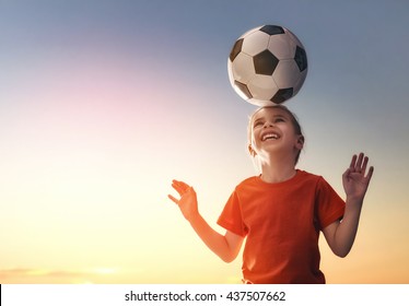 Cute little child dreams of becoming a soccer player. Girl plays football.